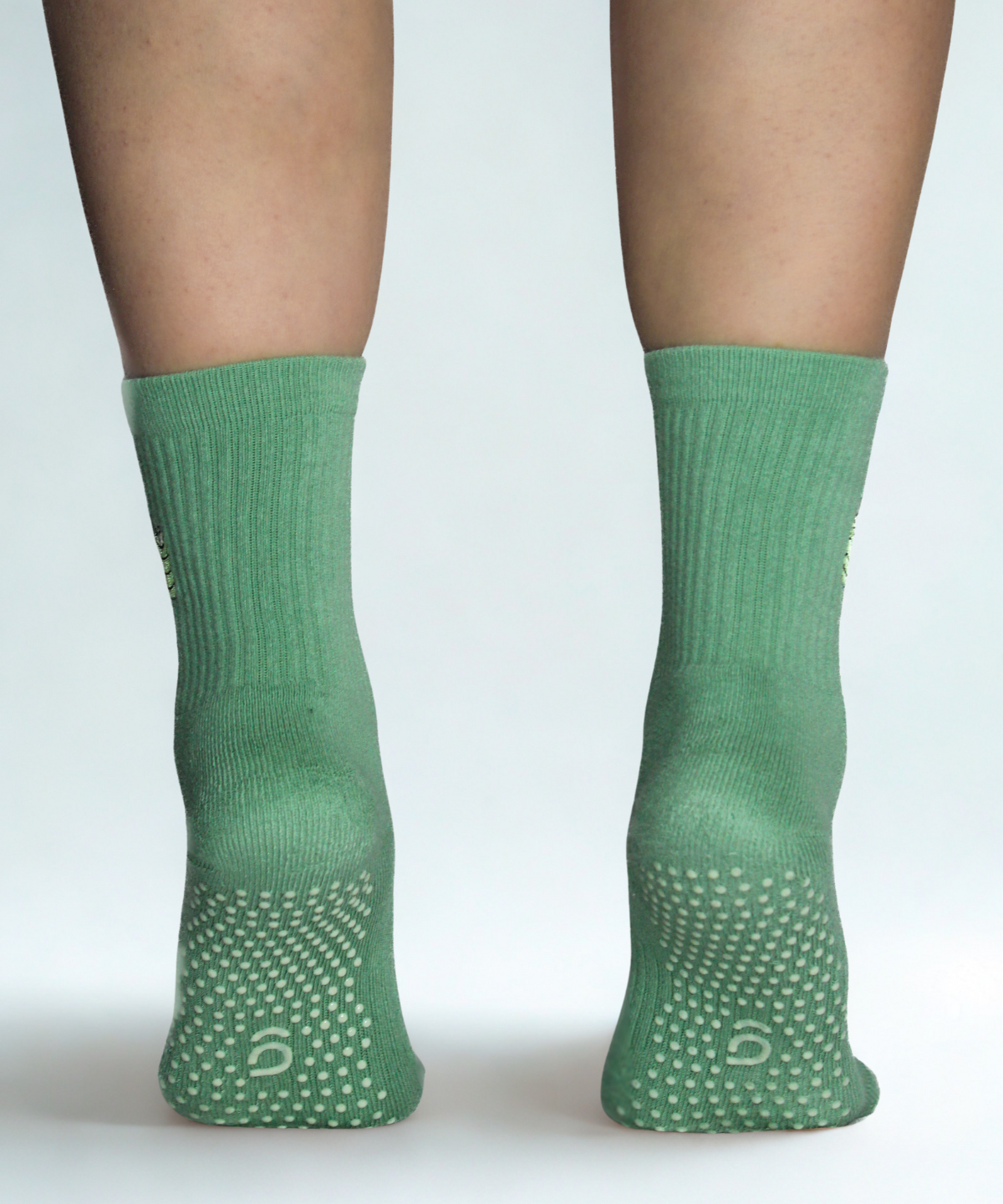 Green socks with textured sole on a white background