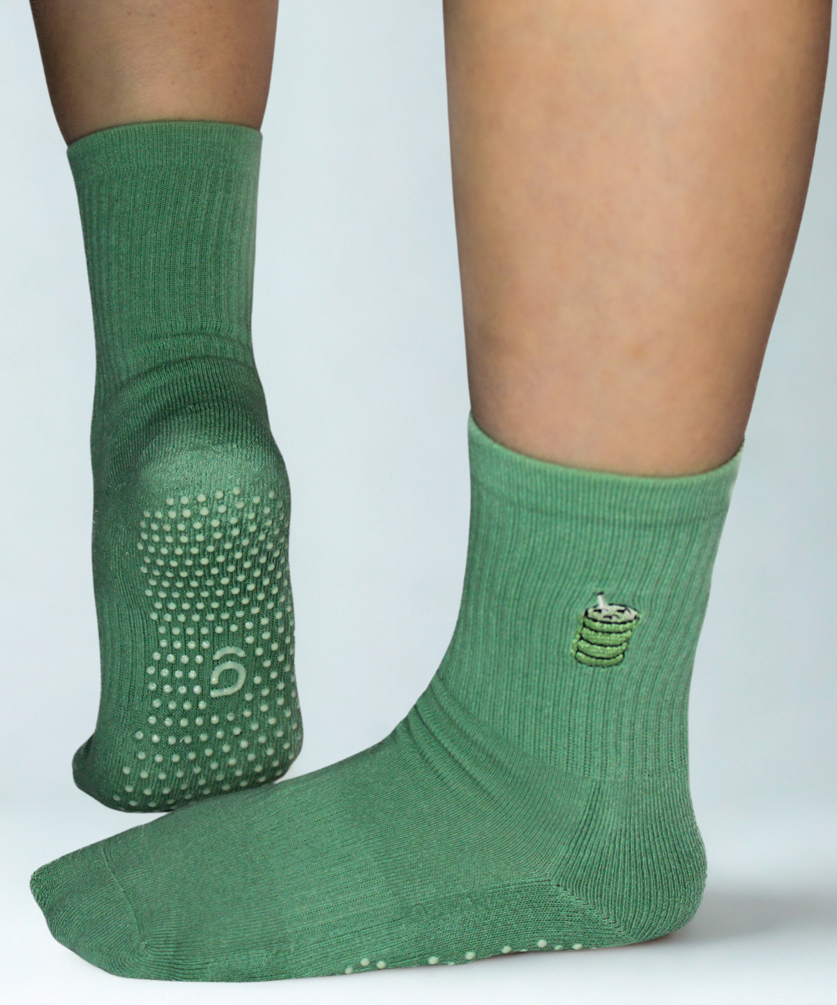 Green socks with textured sole and brand logo on a light gray background