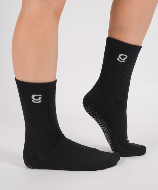 Black socks with a logo on the toes worn by a person on a white background