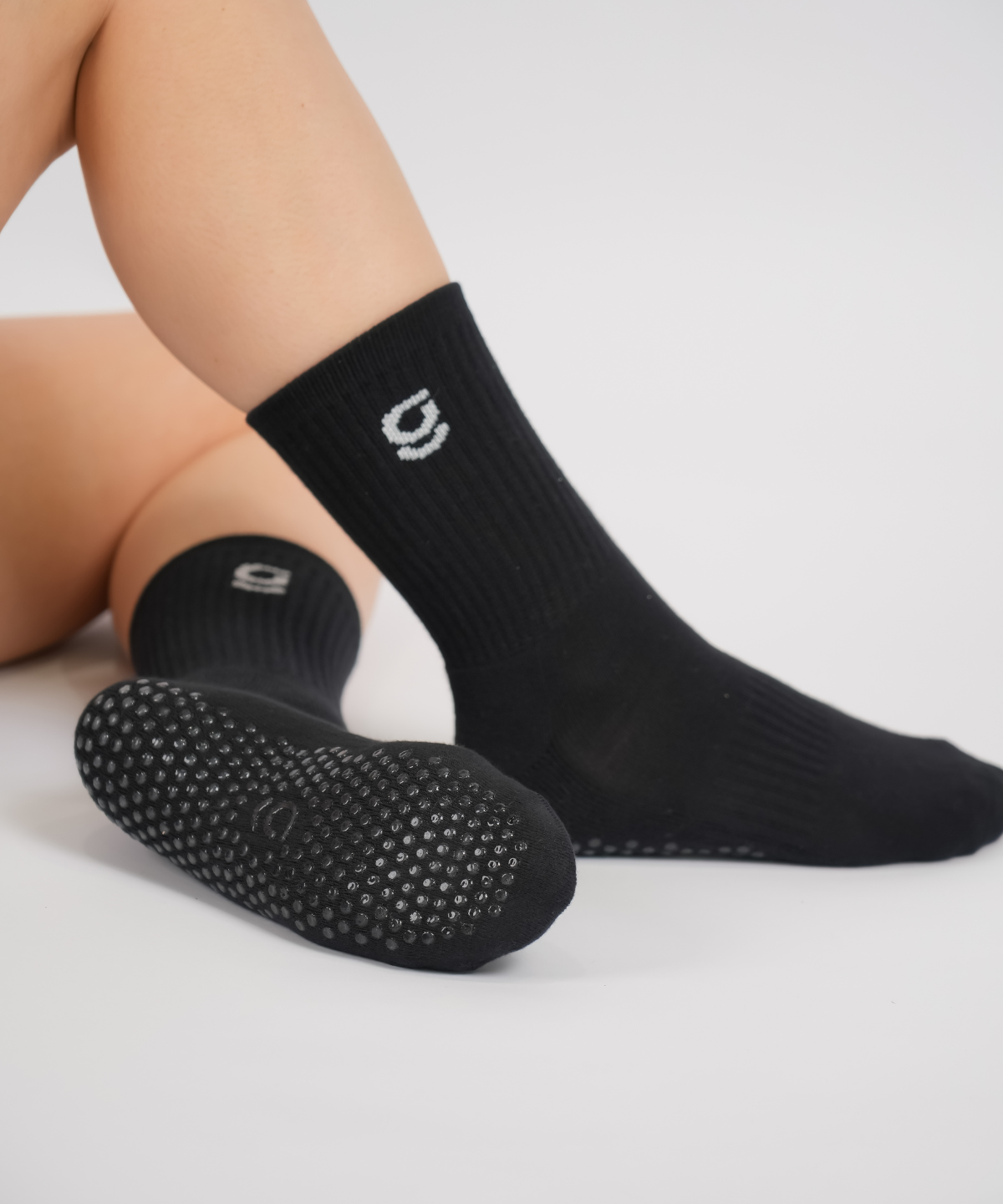 Black socks with grips sole and brand logo on a light gray background
