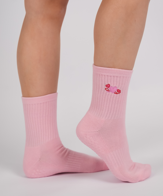Pink socks with a heart design worn by a person on a light gray background