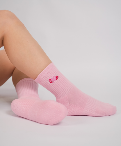 Pink socks with a heart design on a light gray background