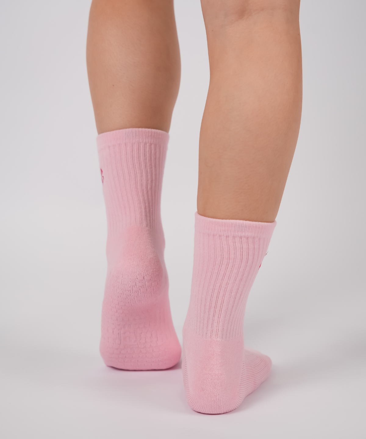Pink socks worn by a person on a light gray background