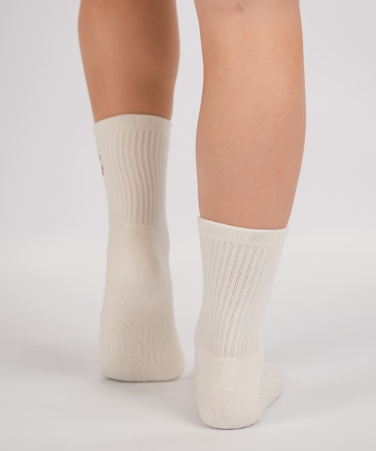 White socks with cherry design worn by a person on a light gray background
