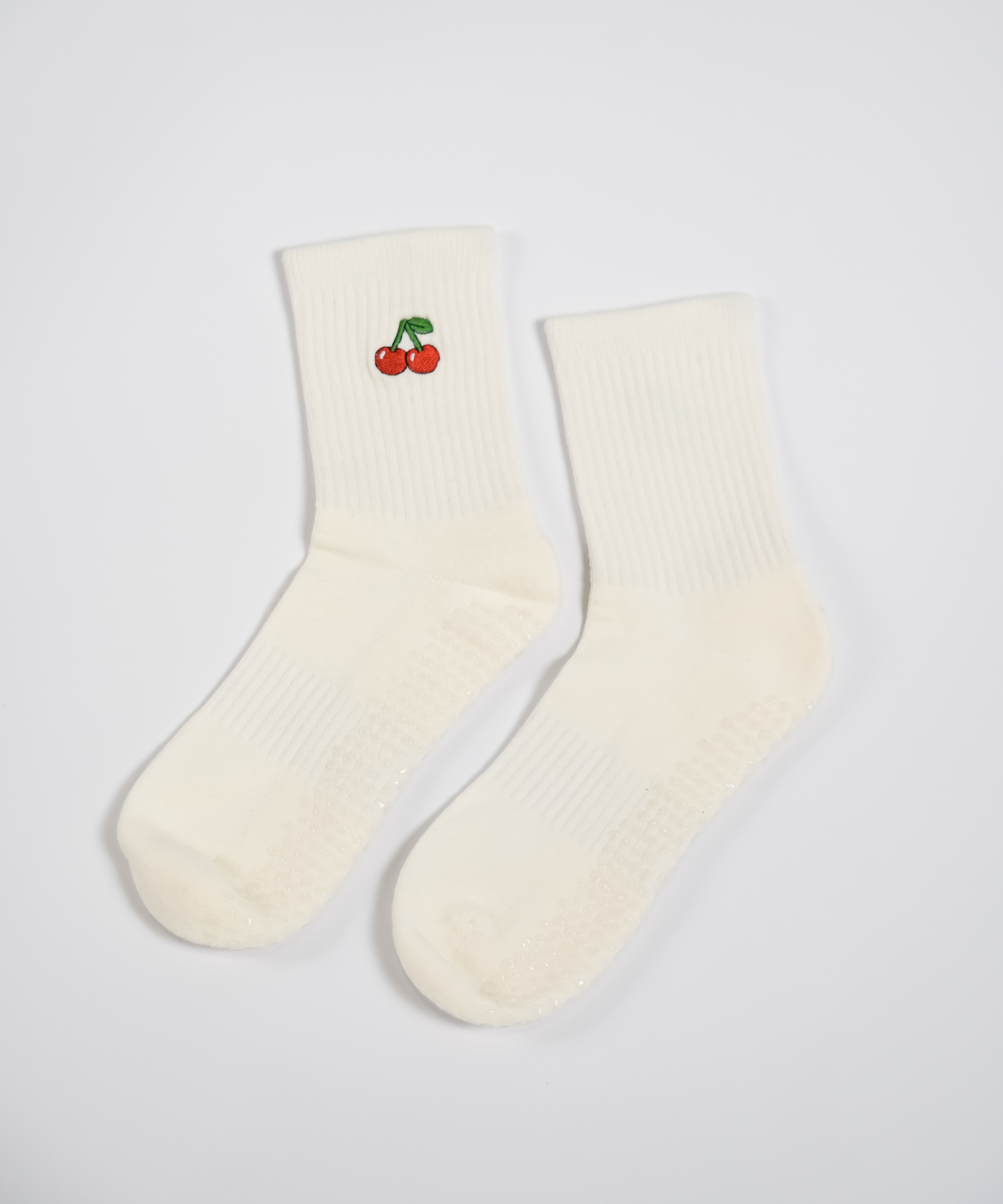 Pair of cream socks with a cherry design on a light gray background